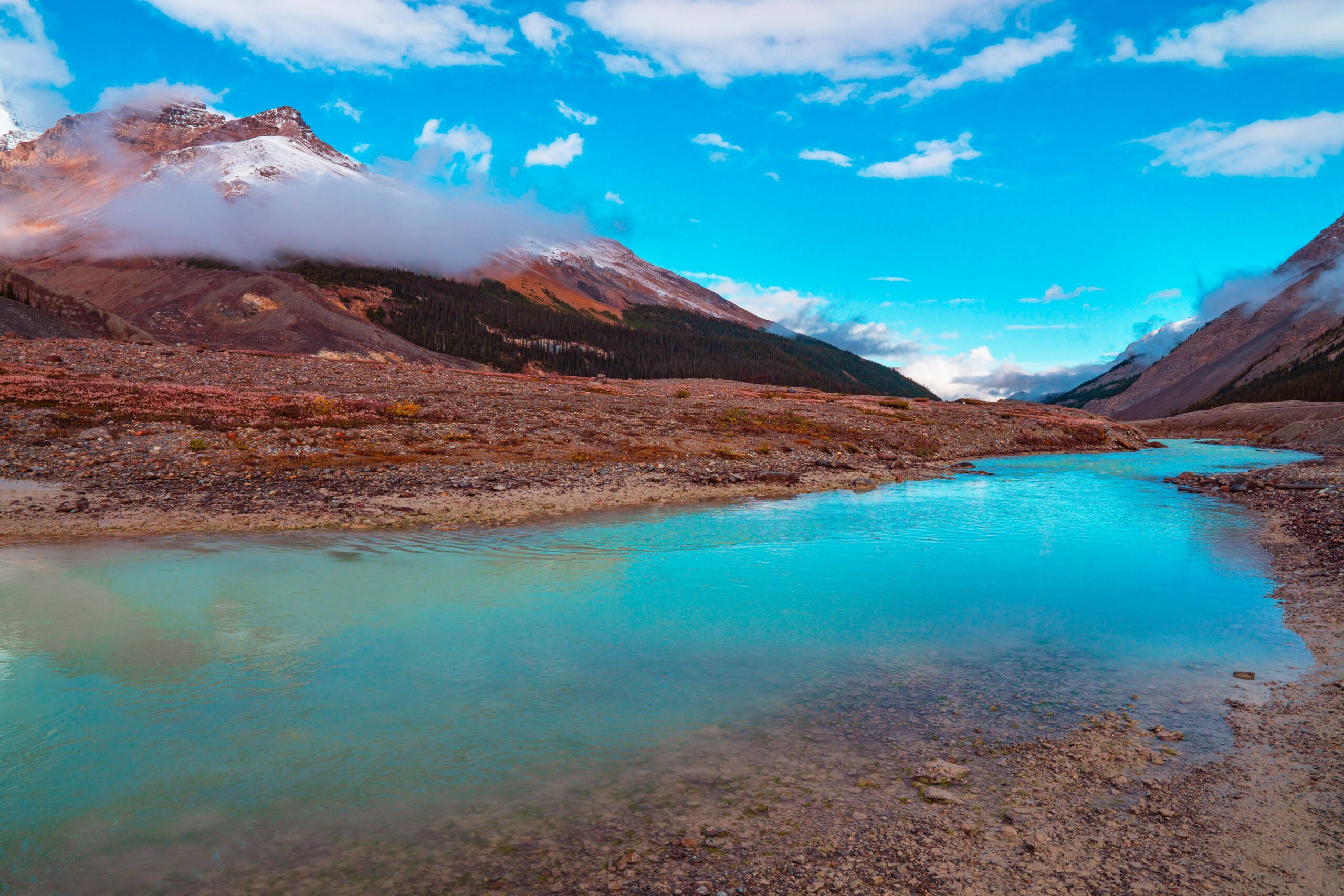 brown and white mountain near body of water under blue sky during daytime