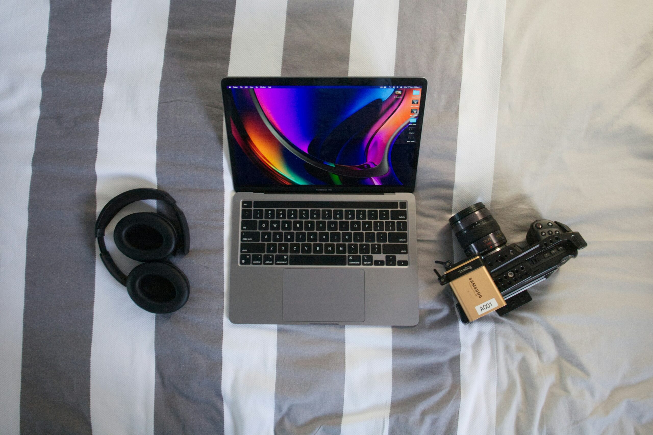 a laptop computer sitting on top of a bed next to a camera